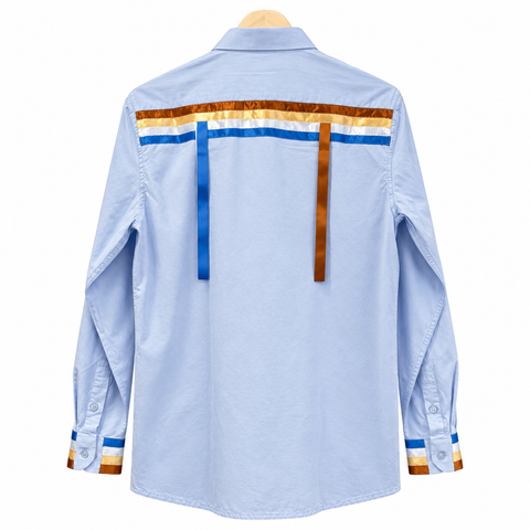 Back view of a light blue Cree ribbon shirt with blue and brown ribbon detailing by Alexandria Coon of Mistissini.